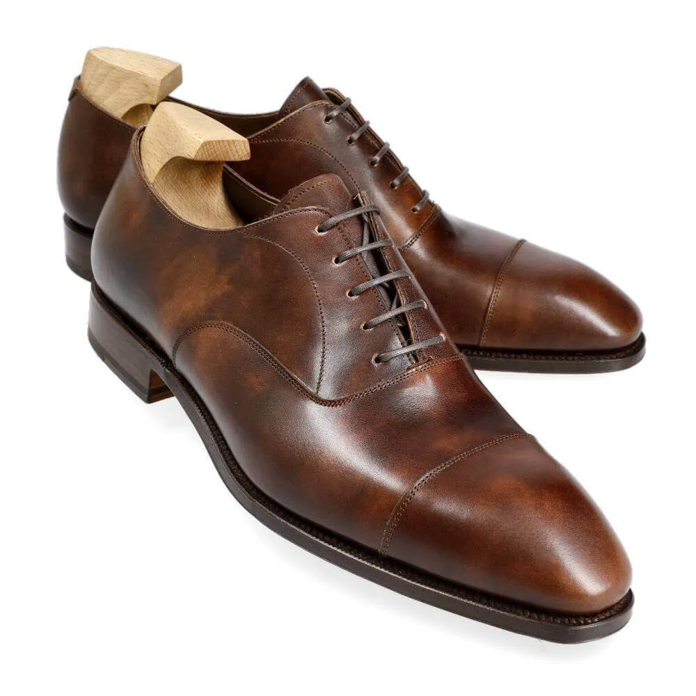 Brown leather dress shoes with a sleek design and wooden shoe trees.