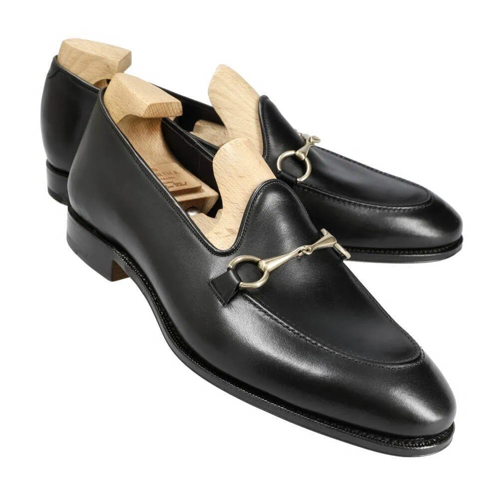 Black leather loafers with a decorative gold-tone bit detail and wooden shoe trees inside.