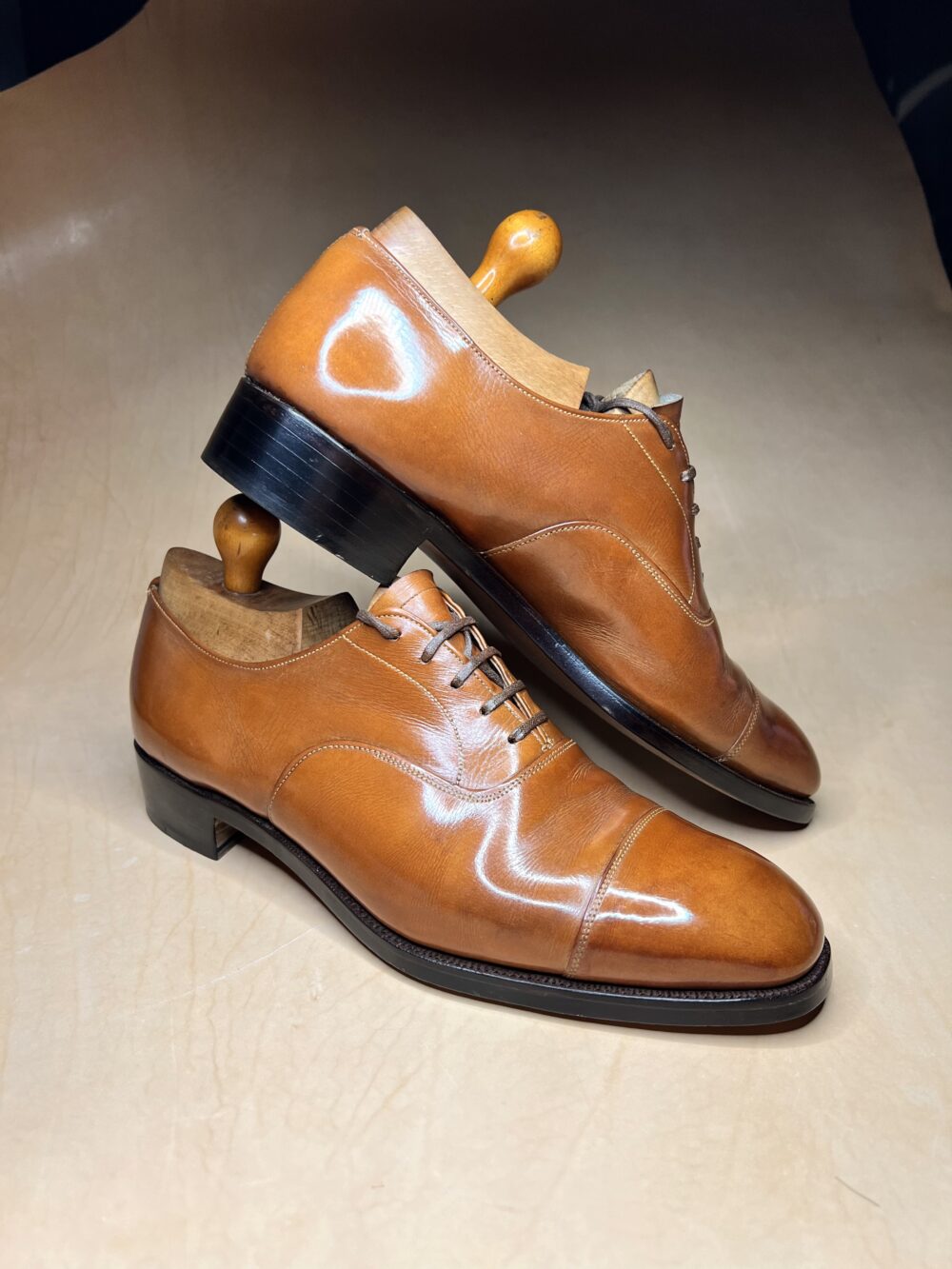A pair of polished tan leather dress shoes with wooden shoe trees, featured for the Americas Shoe Shining Championships.