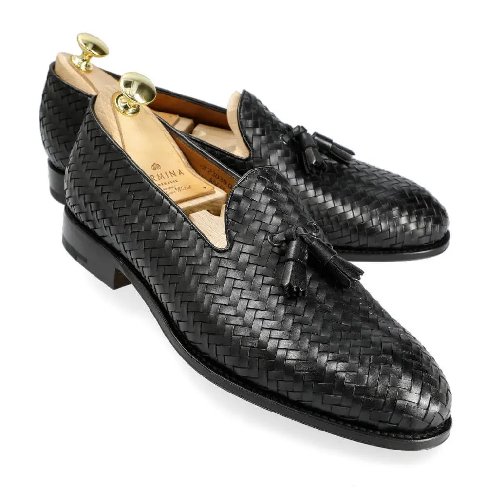 Black woven leather loafers with tassels and shoe trees inside.