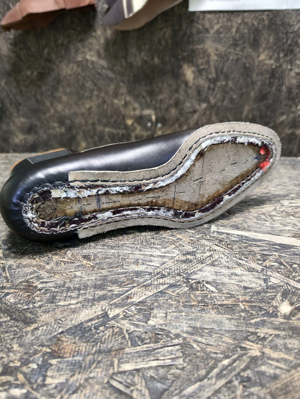A close-up of a black shoe sole showing layered materials and stitching details.