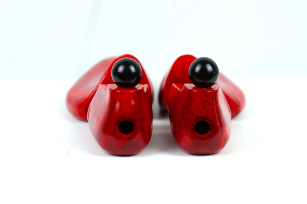 Red wooden shoe trees with black spherical knobs on top.