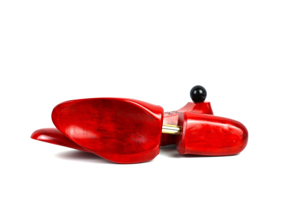 Red wooden shoe trees with a shiny finish and a black knob.