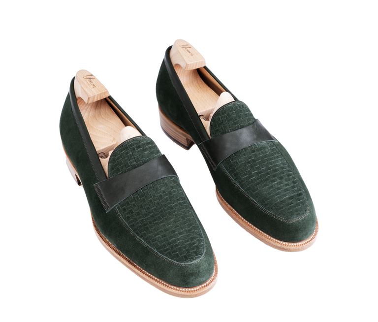 A pair of dark green suede Amalfi loafers with a black leather strap and wooden shoe trees inside.
