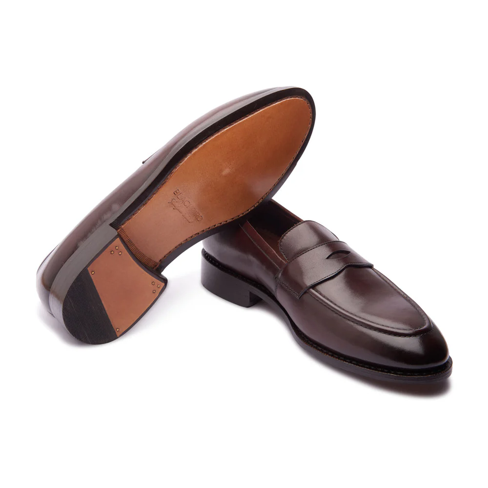 A pair of dark brown leather loafers with a sleek design and a contrasting light brown sole.