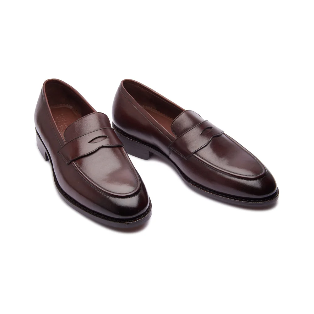 A pair of dark brown leather loafers with a decorative strap across the front.