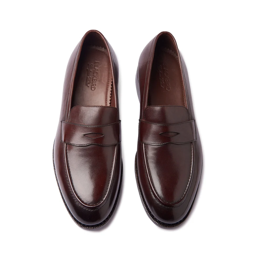 A pair of dark brown leather loafers with a sleek design and a subtle decorative stitch.