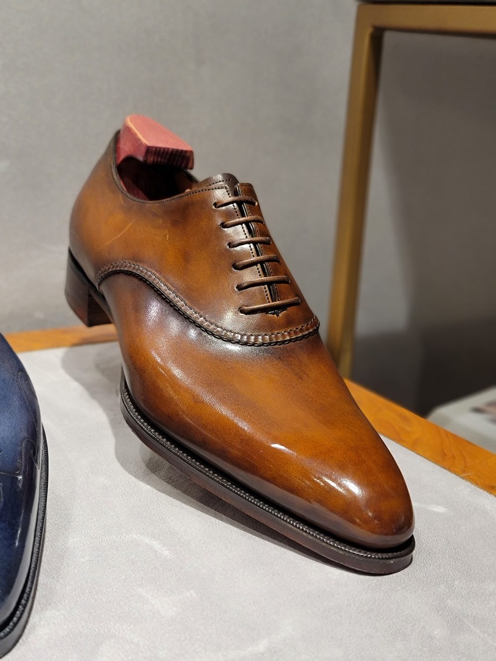 A polished brown leather dress shoe with a lace-up design and a pointed toe.
