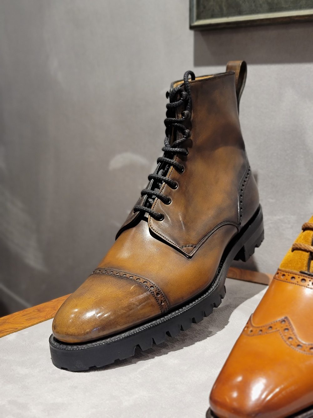 A brown leather boot with a cap toe and black laces.