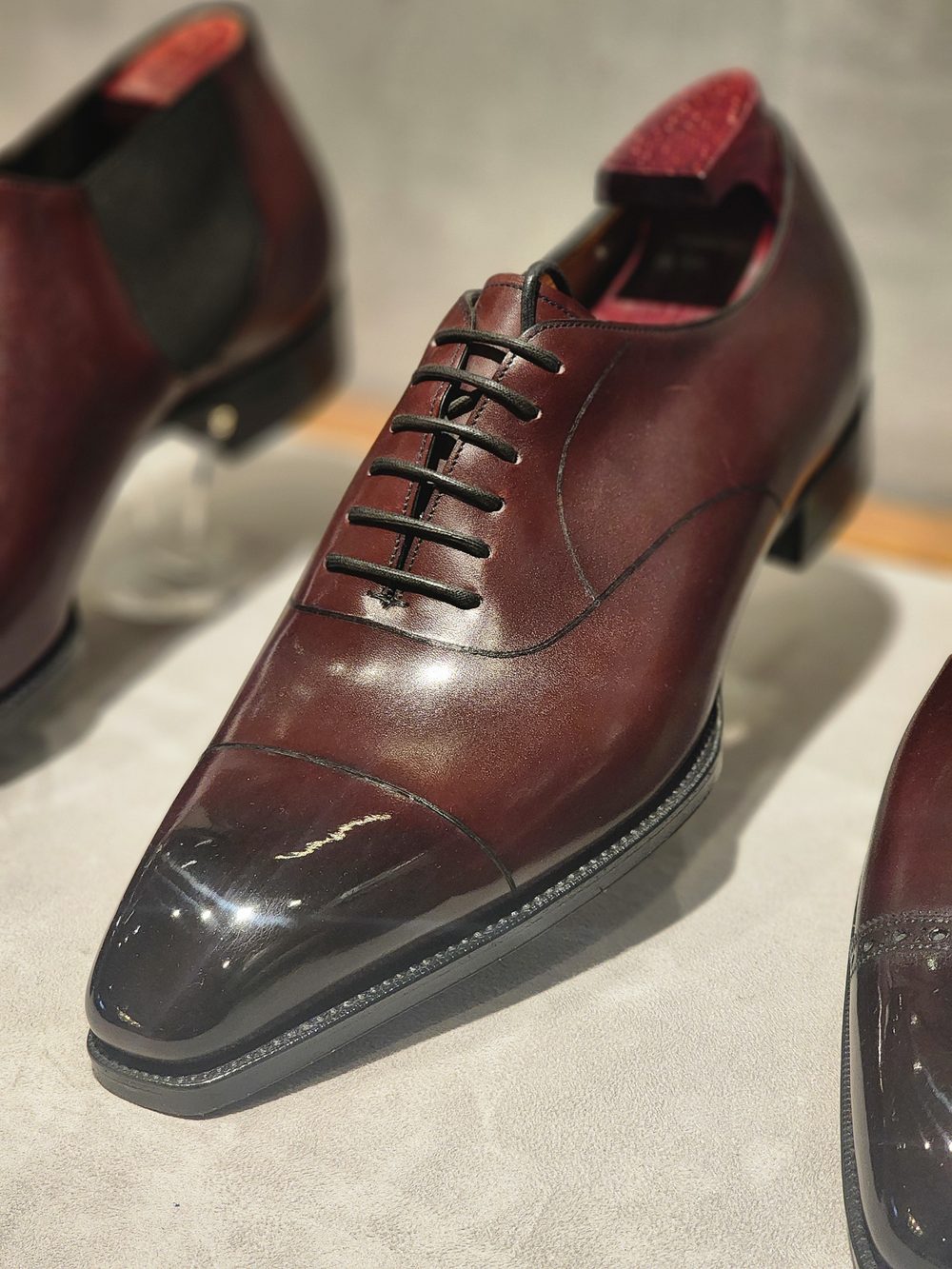 A polished burgundy leather dress shoe with a cap toe and black laces.