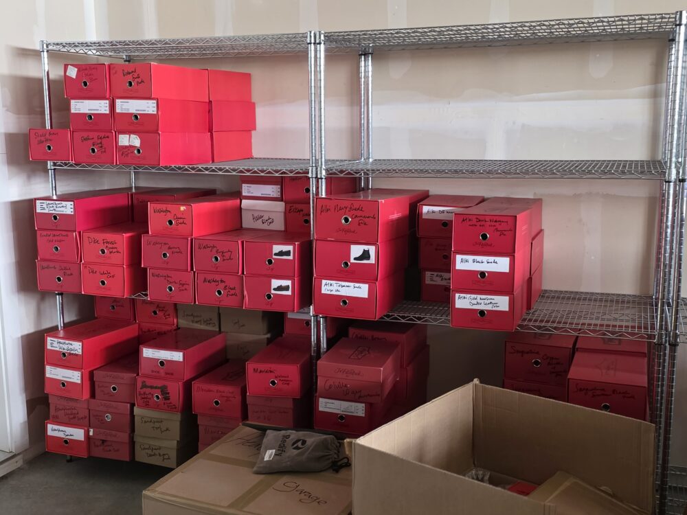 A shelf filled with labeled red boxes, containing various items, with a brown cardboard box in the foreground.
