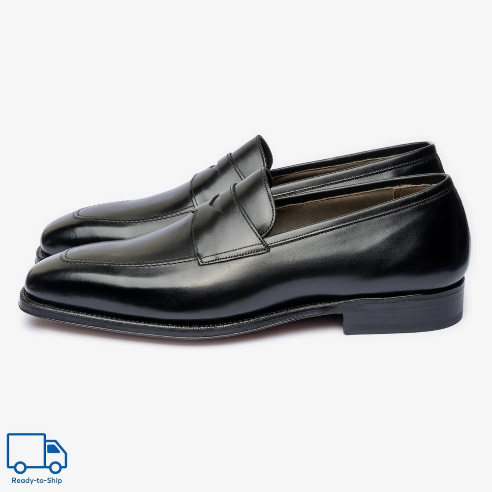 A pair of black leather loafers with a pointed toe and a stitched detail on the upper.