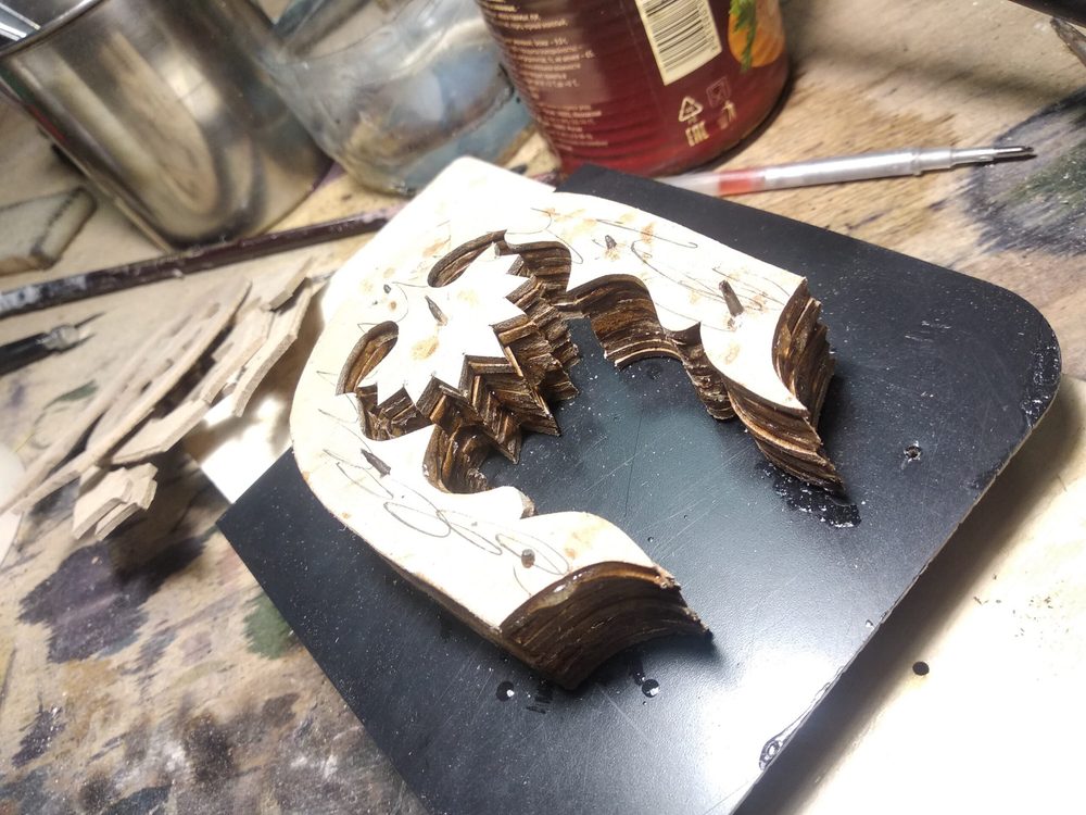 A wooden shoe mold with intricate carvings sits on a black surface.