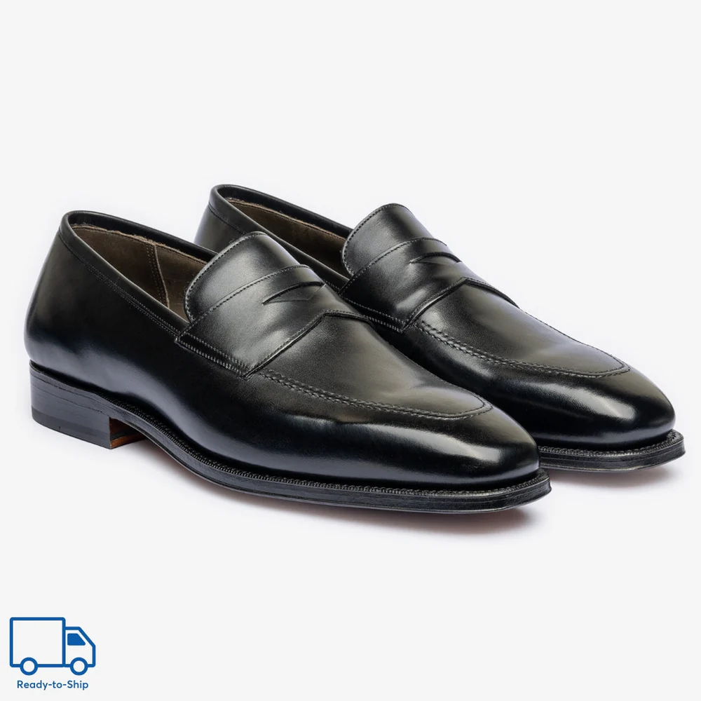 A pair of sleek black leather loafers with a low heel and subtle decorative stitching.