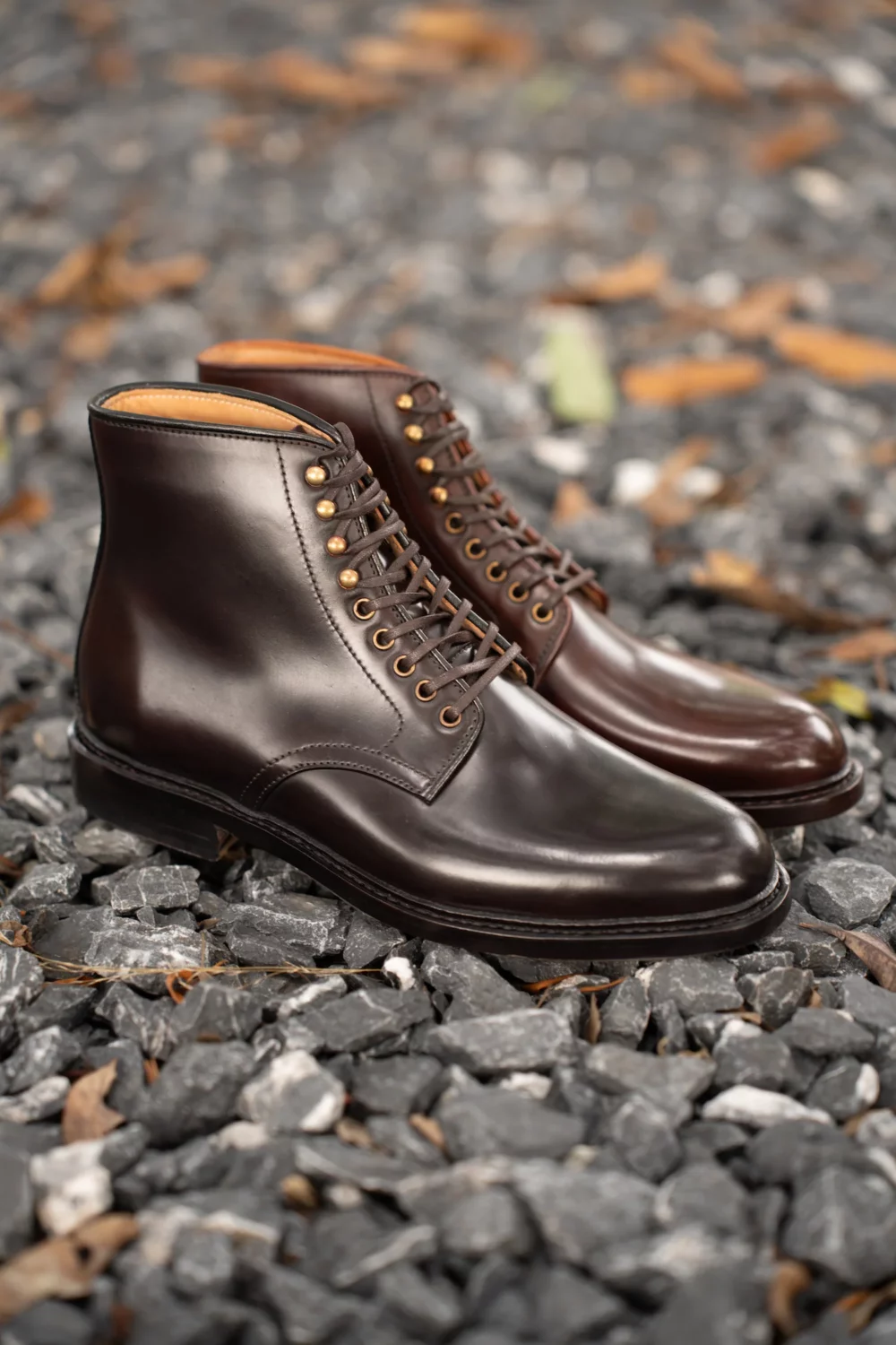 A pair of dark brown leather boots with brass eyelets and laces.