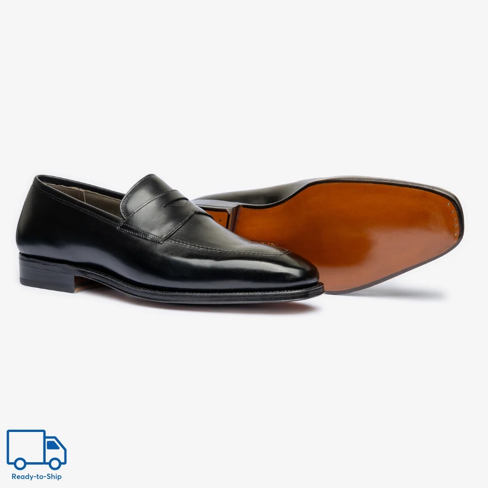 A pair of black leather loafers with a smooth finish and a brown sole.