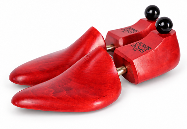 A pair of red wooden shoe trees labeled "The Shoe Snob's Lightweight Shoe Trees" with black knobs on top.