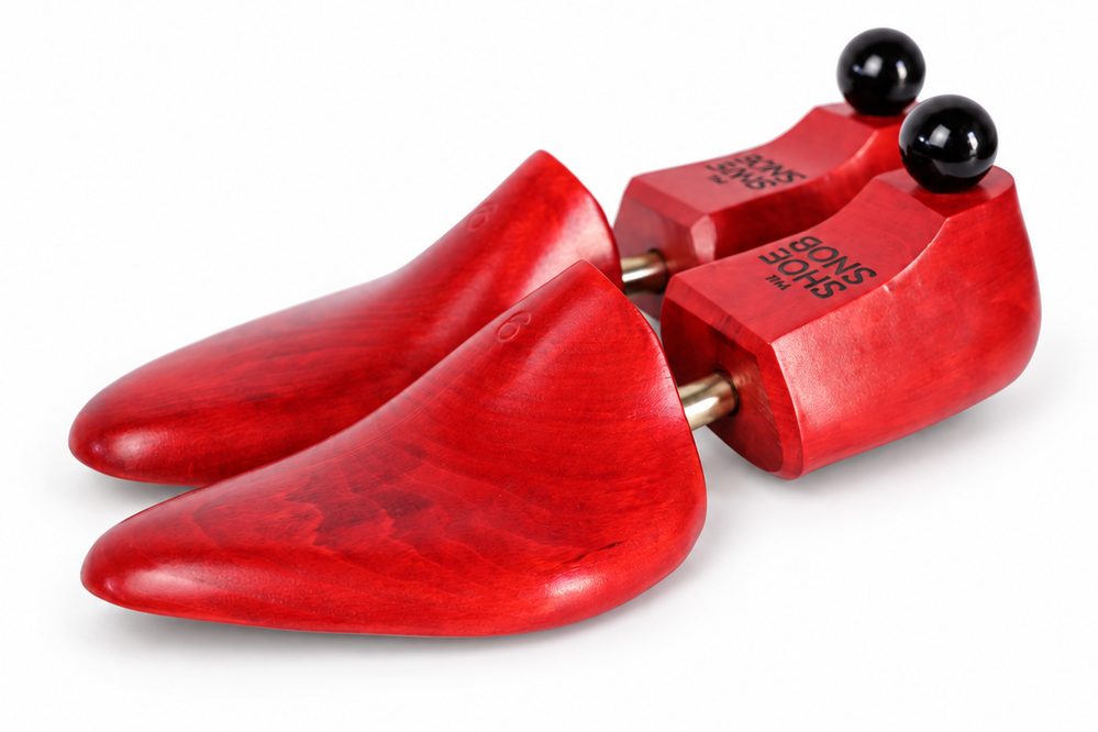 A pair of red wooden shoe trees labeled "The Shoe Snob's Lightweight Shoe Trees" with black knobs on top.
