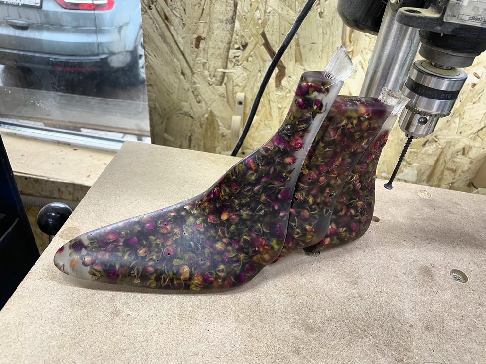 A transparent shoe mold filled with dried pink and yellow flowers.