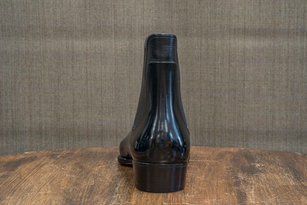 A black leather boot with a sleek design, shown from the back.