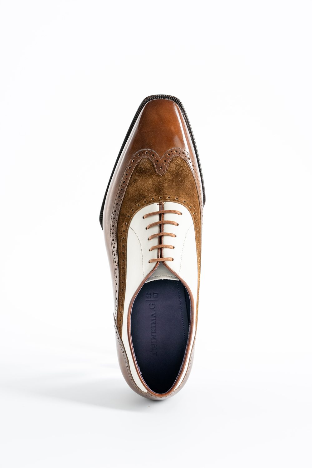 A brown and white leather spectator shoe with a glossy finish and decorative perforations.