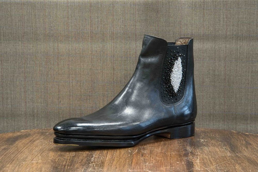 A black leather ankle boot featuring a decorative panel with white and black beads.