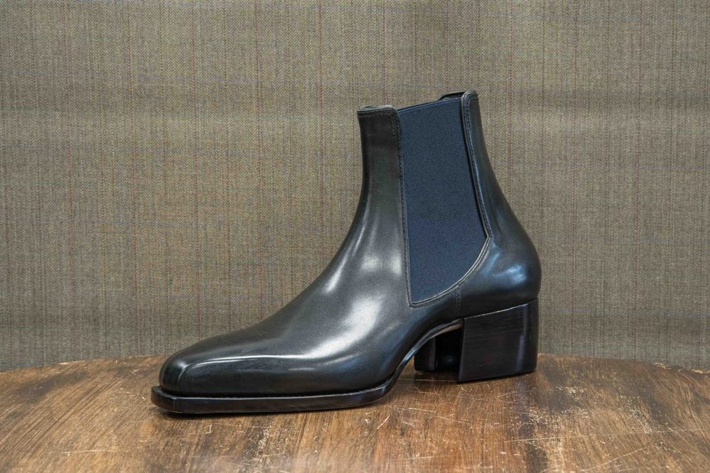 A sleek black leather ankle boot with a block heel and elastic side panels.