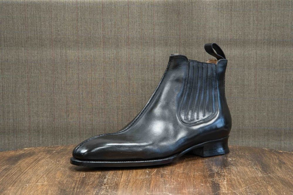 A polished black leather ankle boot with a ribbed side panel.