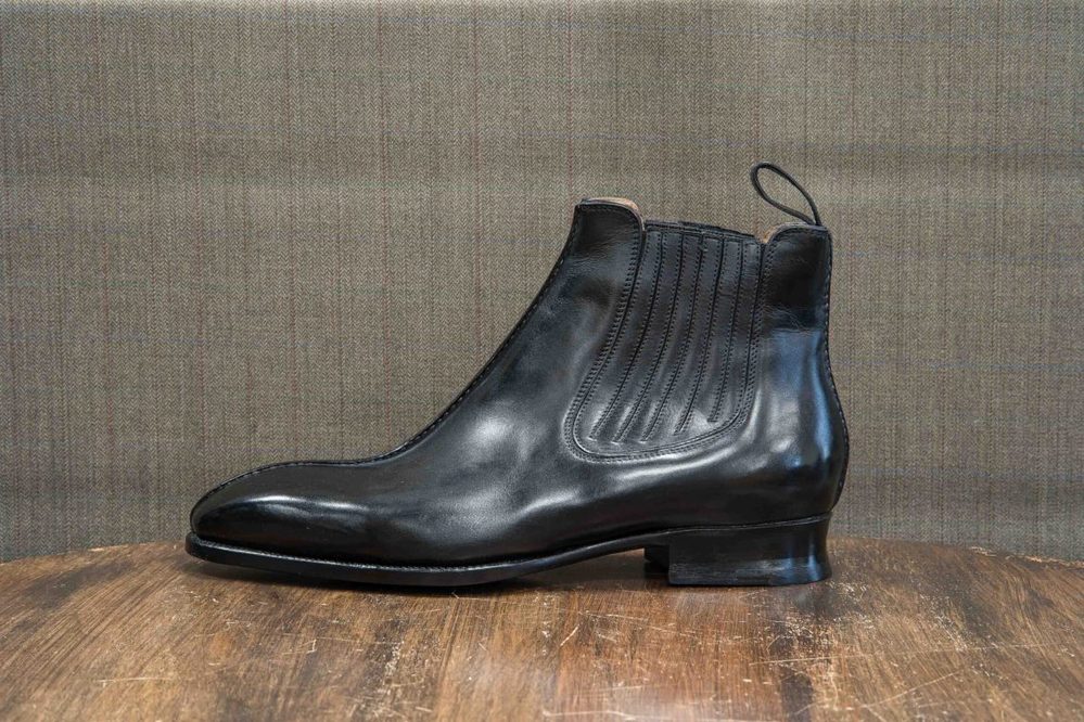 A sleek black leather ankle boot with ribbed detailing on the side.