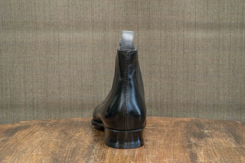 A sleek black leather ankle boot with a silver tab at the heel.