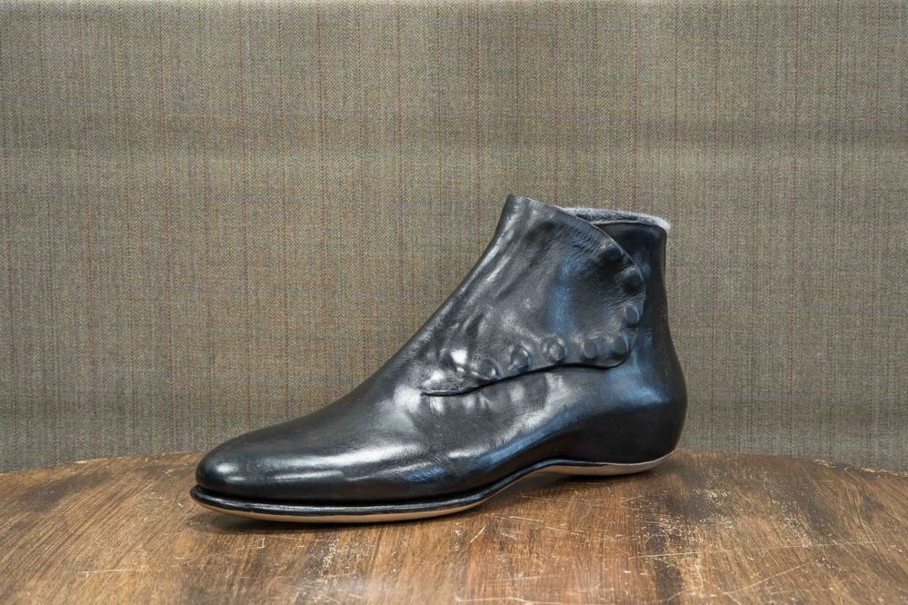 A sleek black leather ankle boot with a unique folded design.