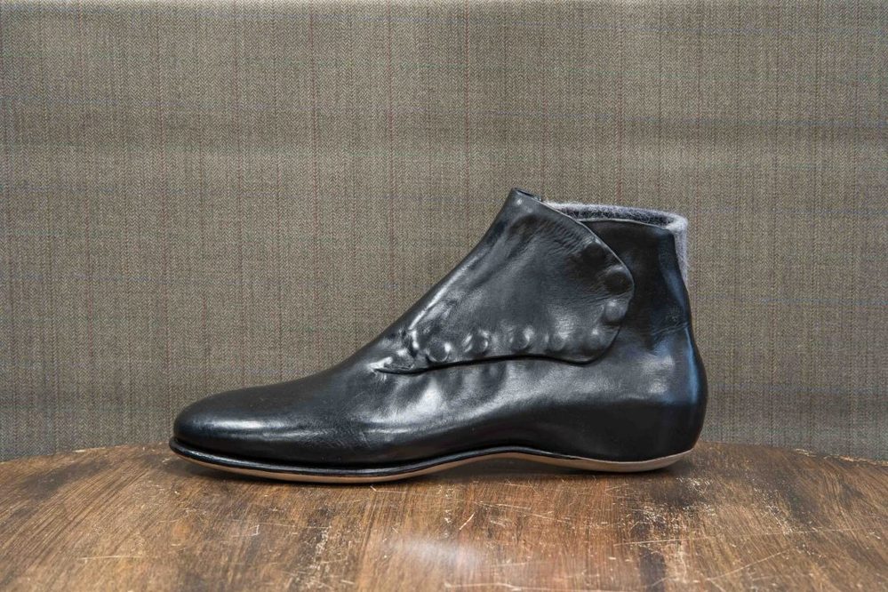 A sleek black leather ankle boot with a unique folded design and smooth finish.
