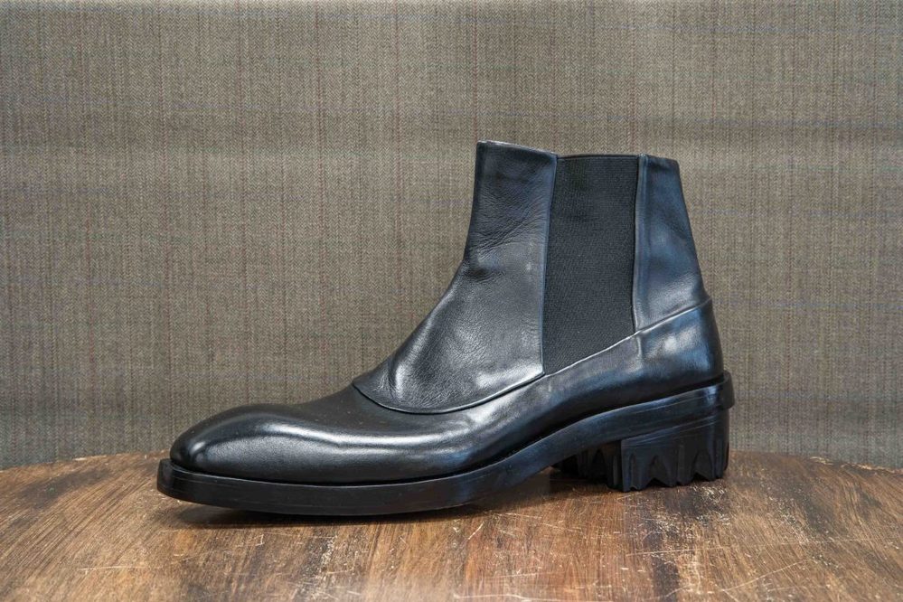 A black leather ankle boot with elastic side panels and a textured heel.