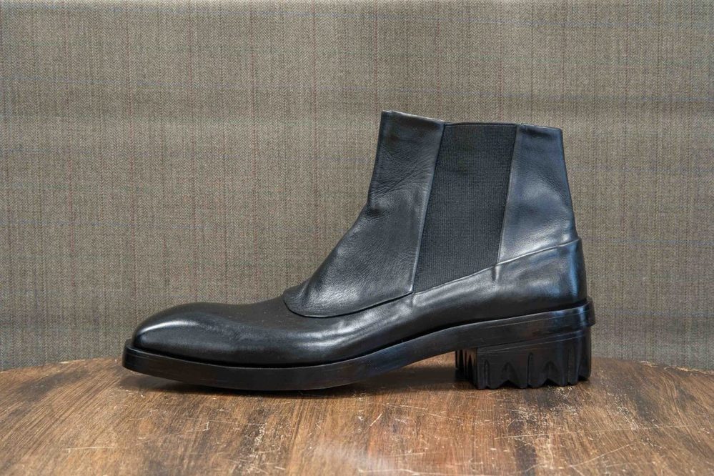 A black leather ankle boot with a chunky sole and elastic panels.