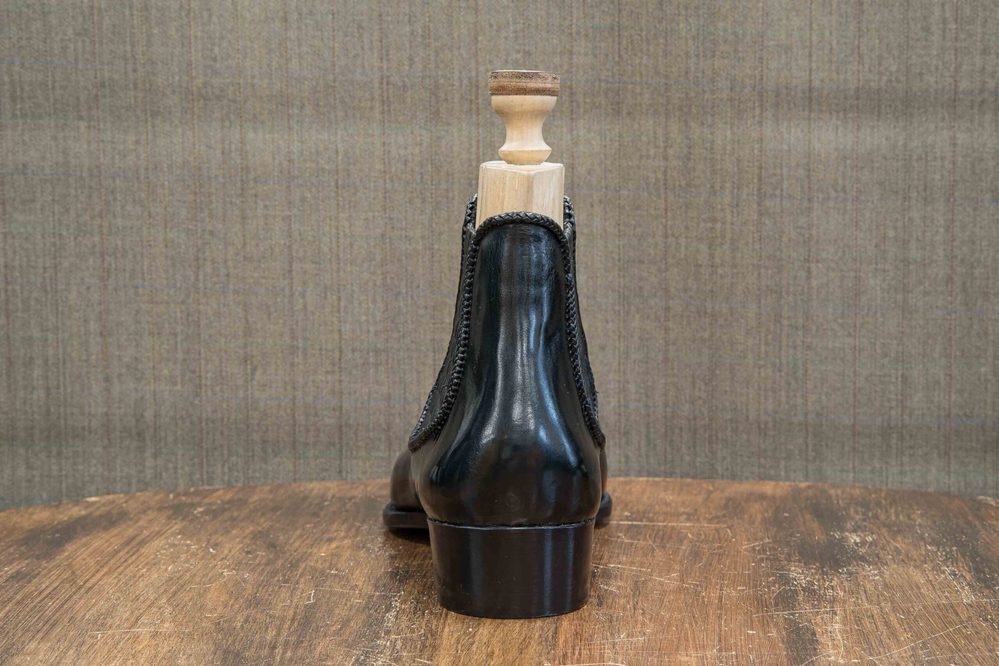 Black leather shoe with a wooden shoehorn on top.