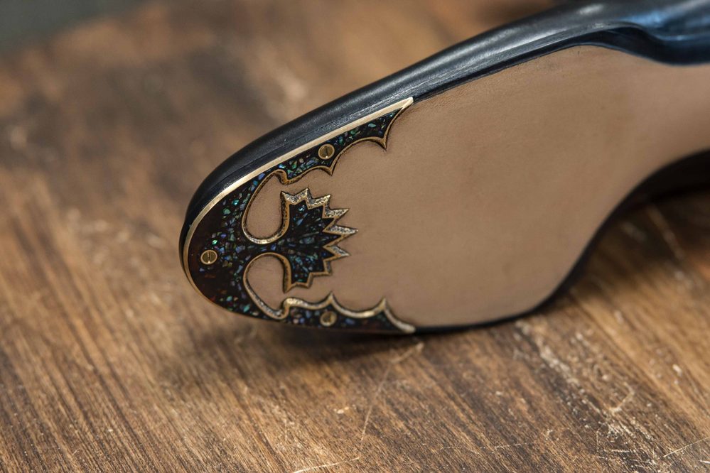 Close-up of a shoe sole featuring intricate black and gold detailing.