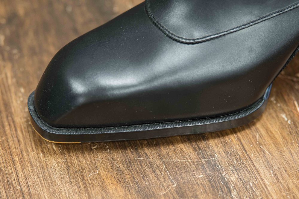 Close-up of a sleek black shoe with a smooth finish and a distinct sole edge.