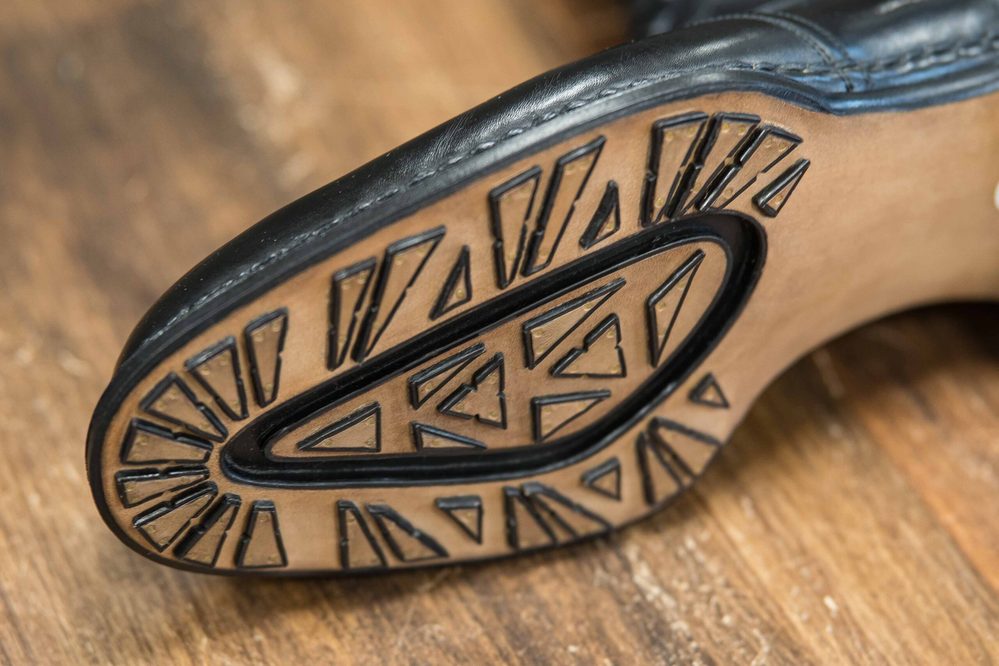 Close-up of a black shoe sole featuring a geometric tread pattern.