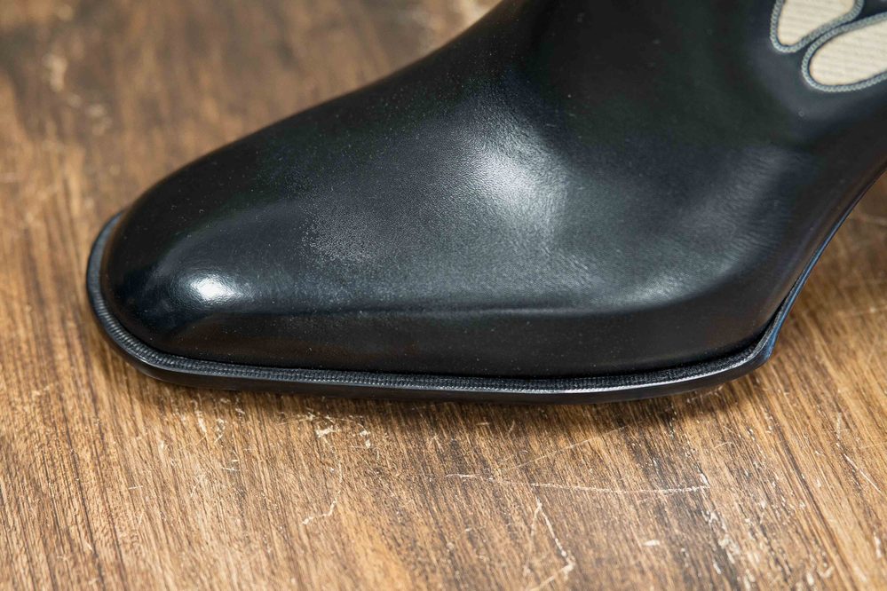 Close-up of a polished black shoe toe with a sleek design.