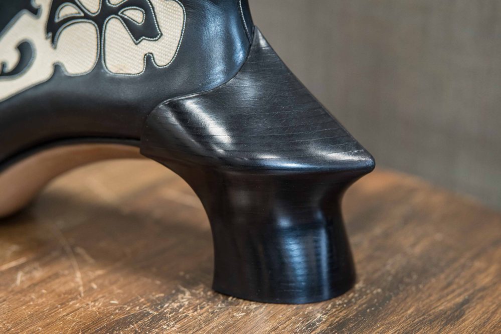 Close-up of a black high heel with a sculpted wooden heel.