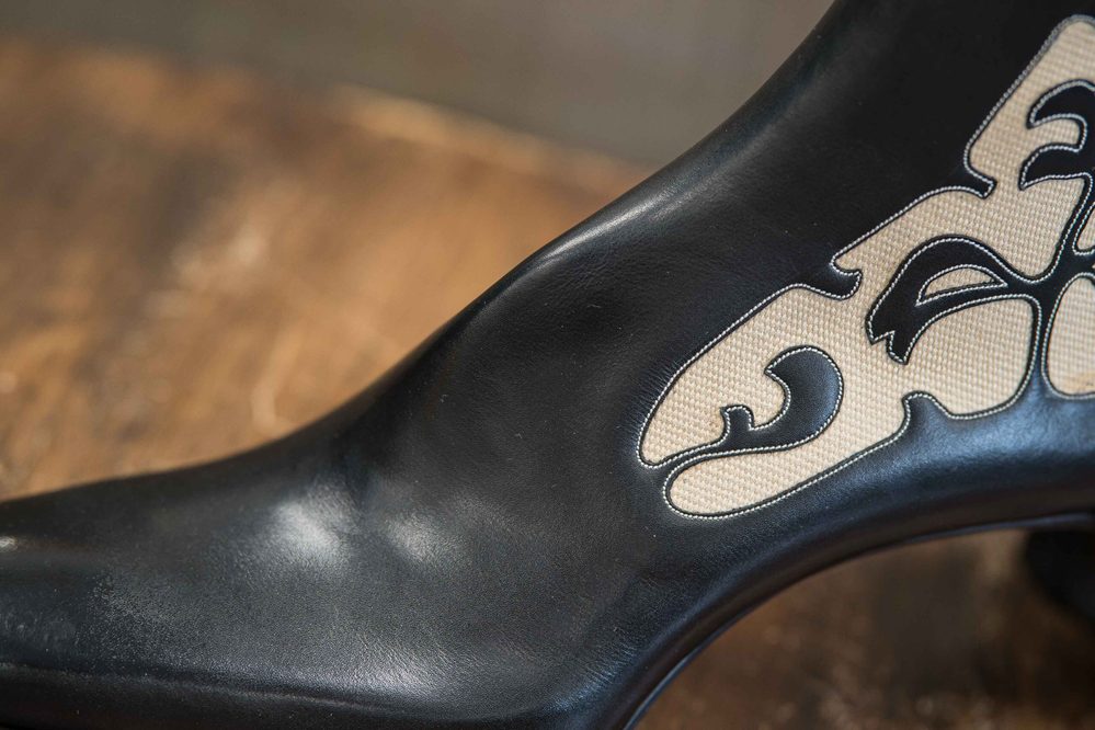 Close-up of a black shoe with a textured beige design on its side.
