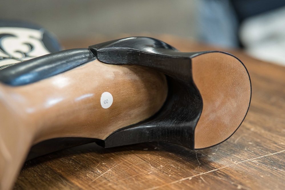 Close-up of a shoe's sole featuring a smooth black edge and a light brown base with a white label.
