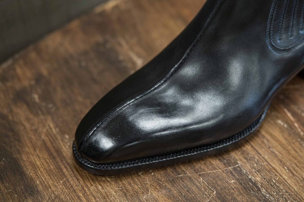 A polished black leather shoe with a pointed toe.