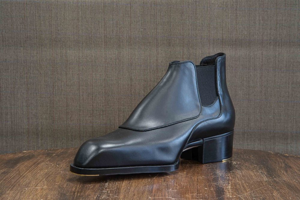 A sleek black leather ankle boot with a square toe and a low block heel.