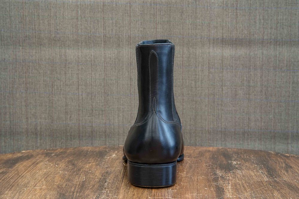 Black leather ankle boot showcasing a smooth finish and a stacked heel.