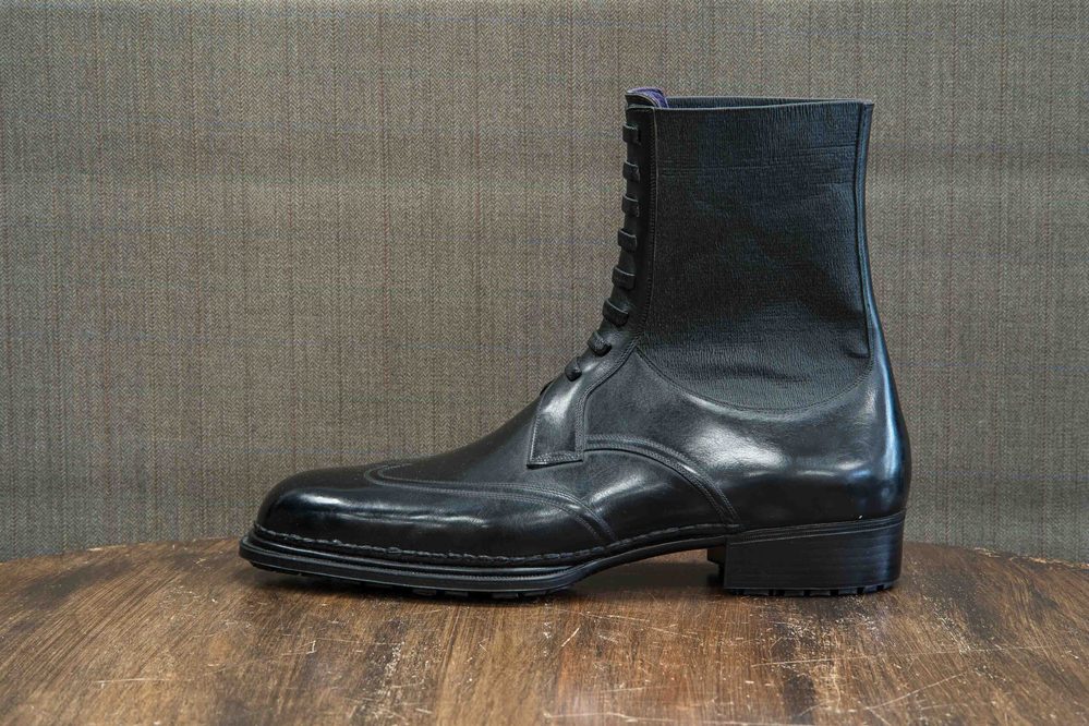 A black leather ankle boot with a lace-up front and a slightly raised heel.