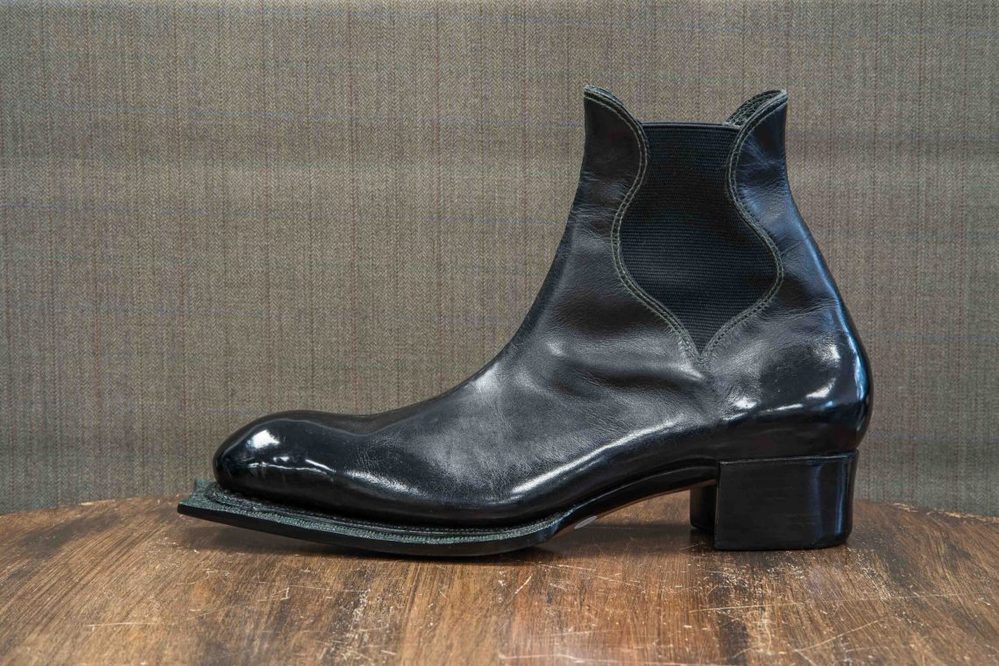 A sleek black leather boot with a unique pointed toe and elastic side panels.