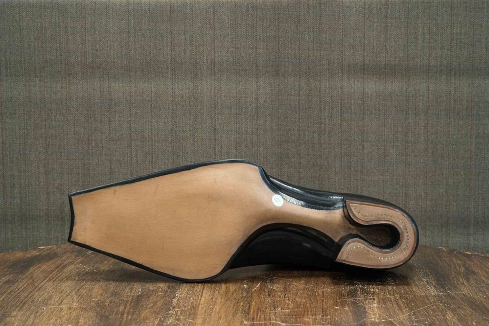 A black shoe sole with a curved design and a light tan insole.