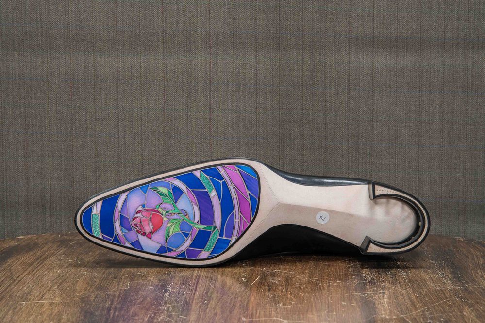 The image shows the sole of a shoe featuring a colorful stained glass design with a rose motif in shades of pink and blue.