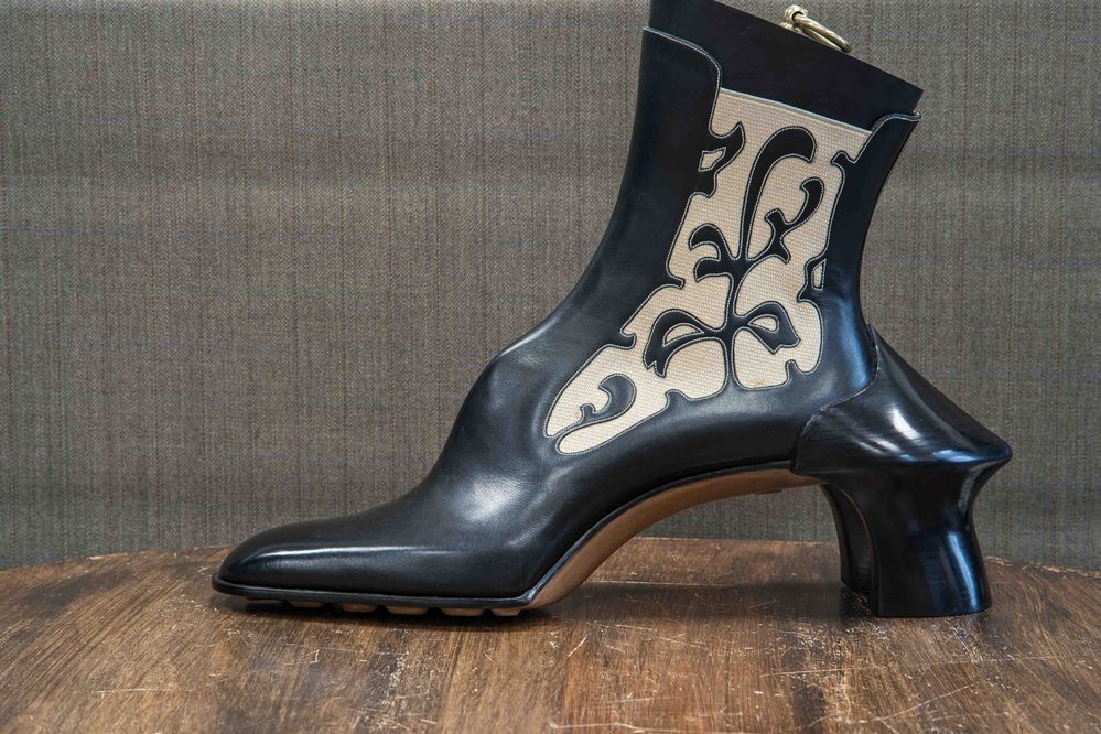 A black and cream ankle boot with an ornate design and a unique sculpted heel.